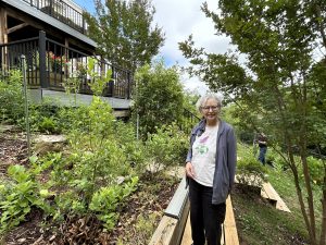 Woman standing among plants and trees in her backyard