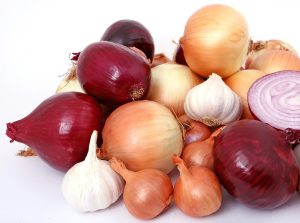 A multi-colored pile of onions and garlic
